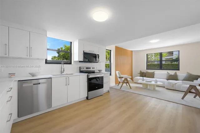 a living room with furniture a fireplace a flat screen tv and windows