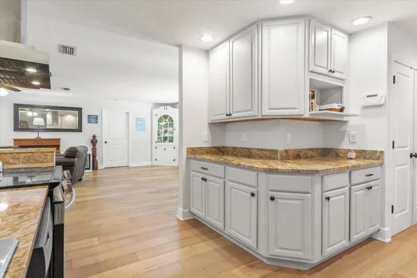 a kitchen with granite countertop a sink a stove cabinets and wooden floor
