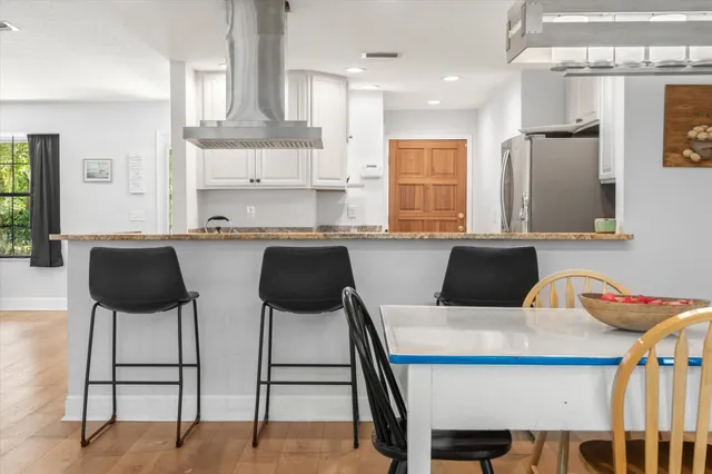 a kitchen with stainless steel appliances kitchen island granite countertop a table chairs and a refrigerator