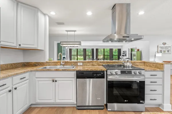 a kitchen with stainless steel appliances granite countertop a stove and a wooden floors