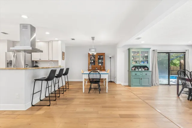 a dining hall with stainless steel appliances kitchen island granite countertop a dining table chairs and view living room