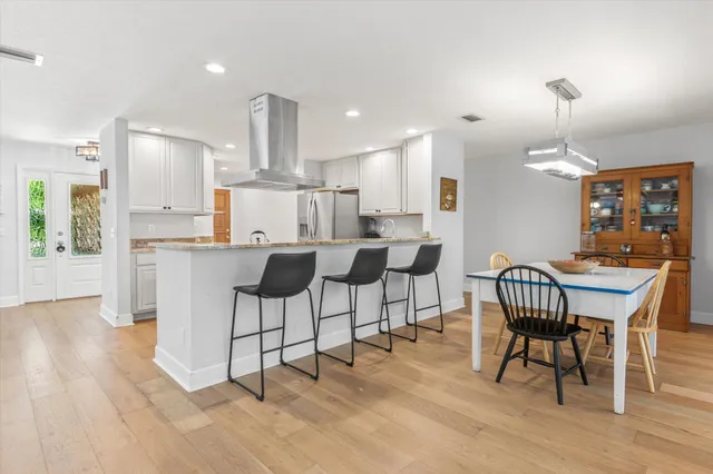 a dining room with kitchen island stainless steel appliances furniture a dining table and chairs with wooden floor