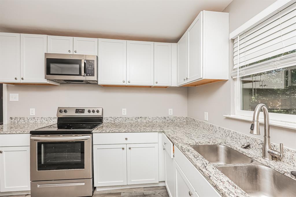 2155 Gaylord Drive Dallas, TX 75227 - Photo 13 of 21 a kitchen with granite countertop a sink dishwasher a stove and a microwave oven with cabinets