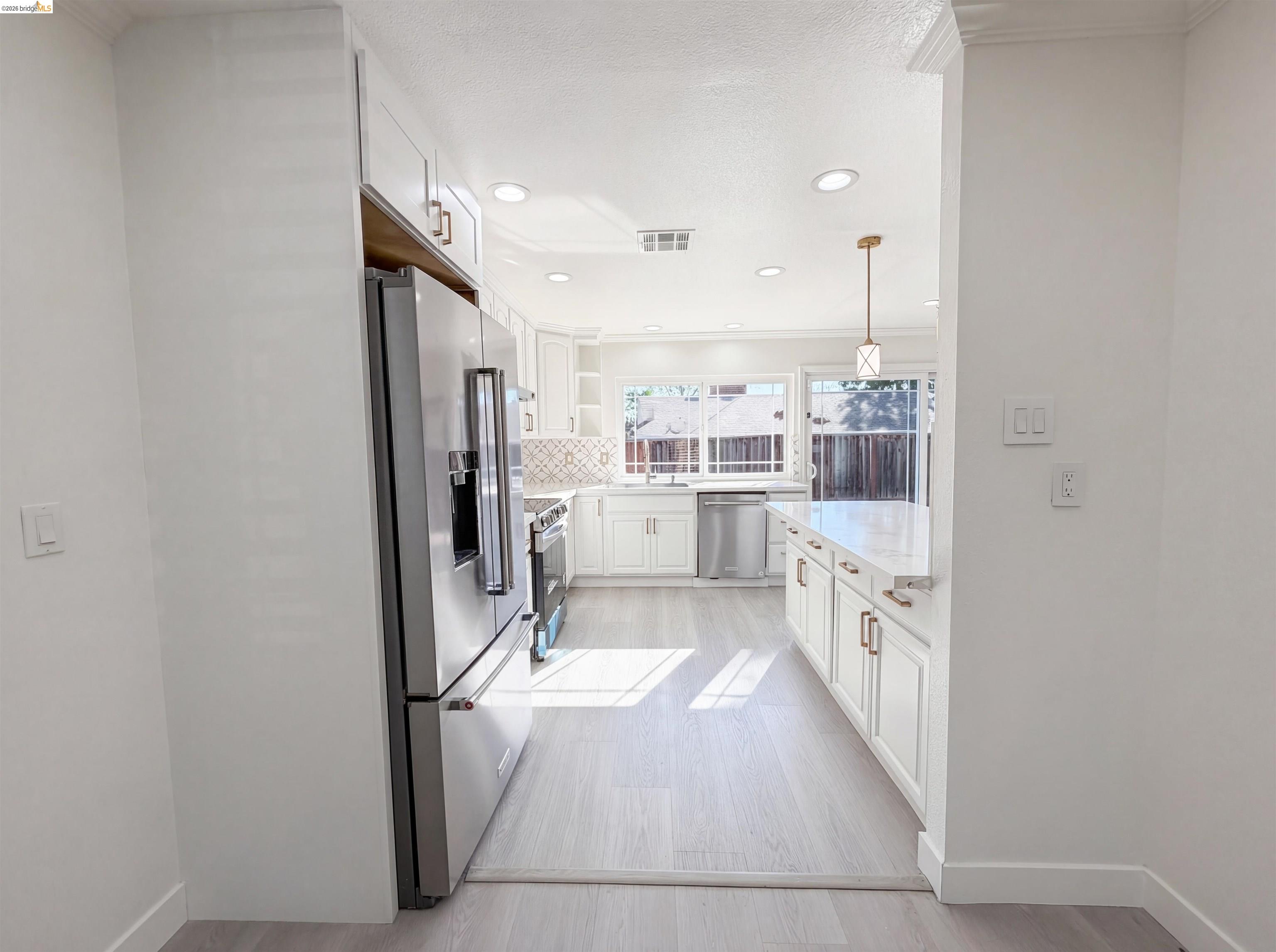 1564 South Wolfe Road Sunnyvale, CA 94087 - Photo 18 of 27 Kitchen with white cabinetry, stainless steel appliances, light wood finished floors, crown molding, and light stone countertops
