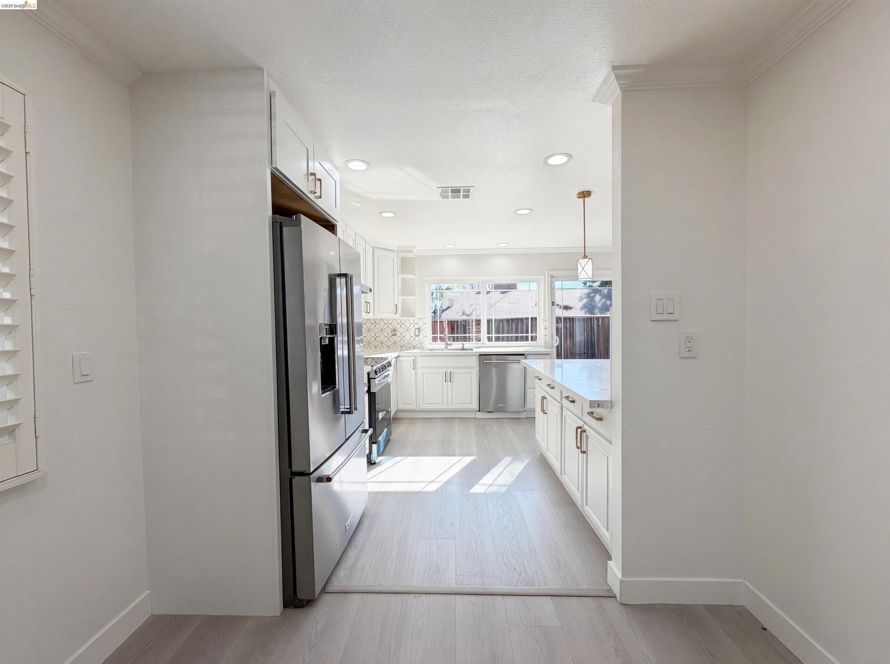 1564 South Wolfe Road Sunnyvale, CA 94087 - Photo 19 of 27 Kitchen with white cabinets, crown molding, stainless steel appliances, and light wood-style floors