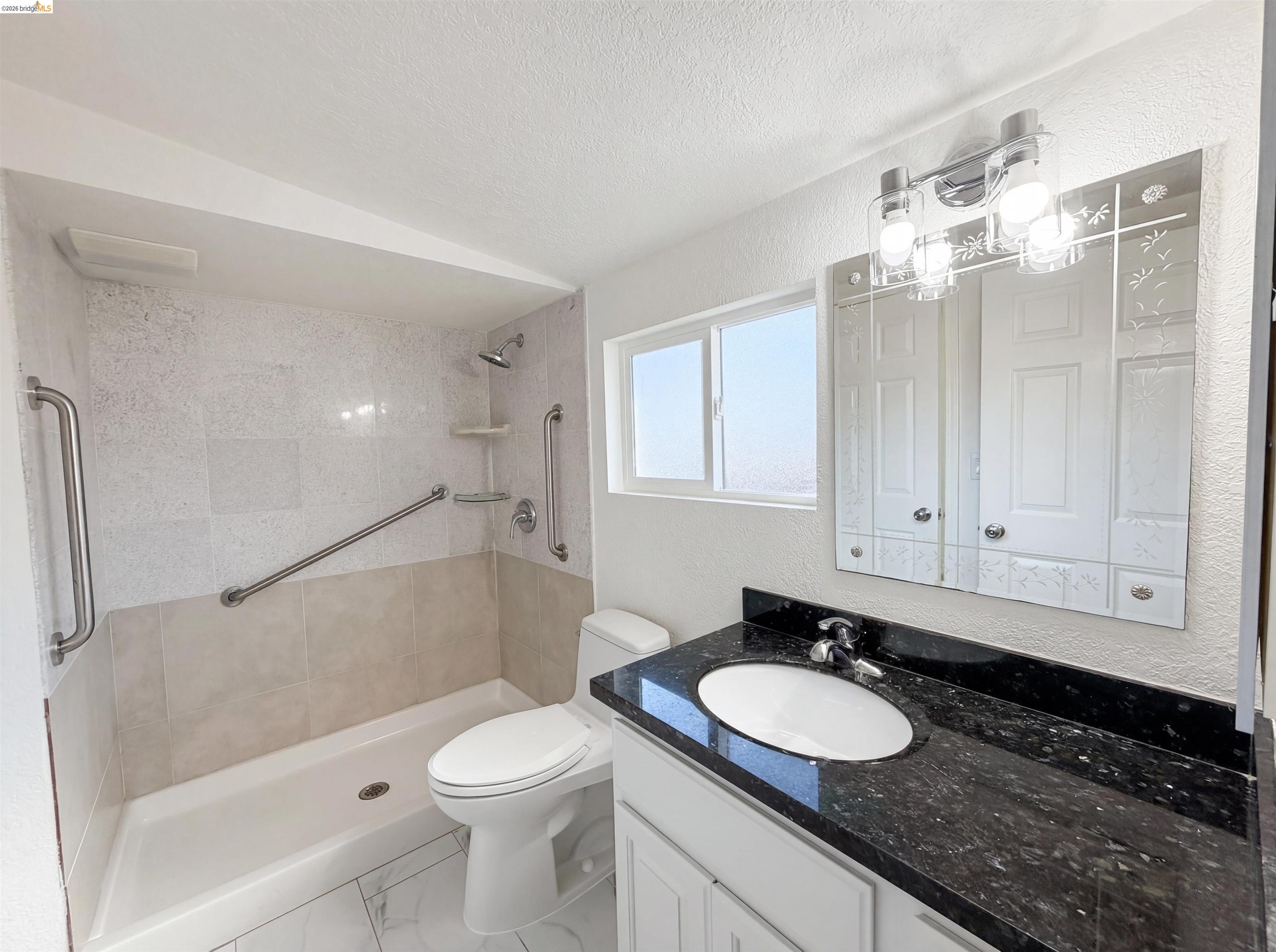 1564 South Wolfe Road Sunnyvale, CA 94087 - Photo 22 of 27 Full bathroom featuring vanity, a tile shower, a textured wall, a textured ceiling, and marble finish floors