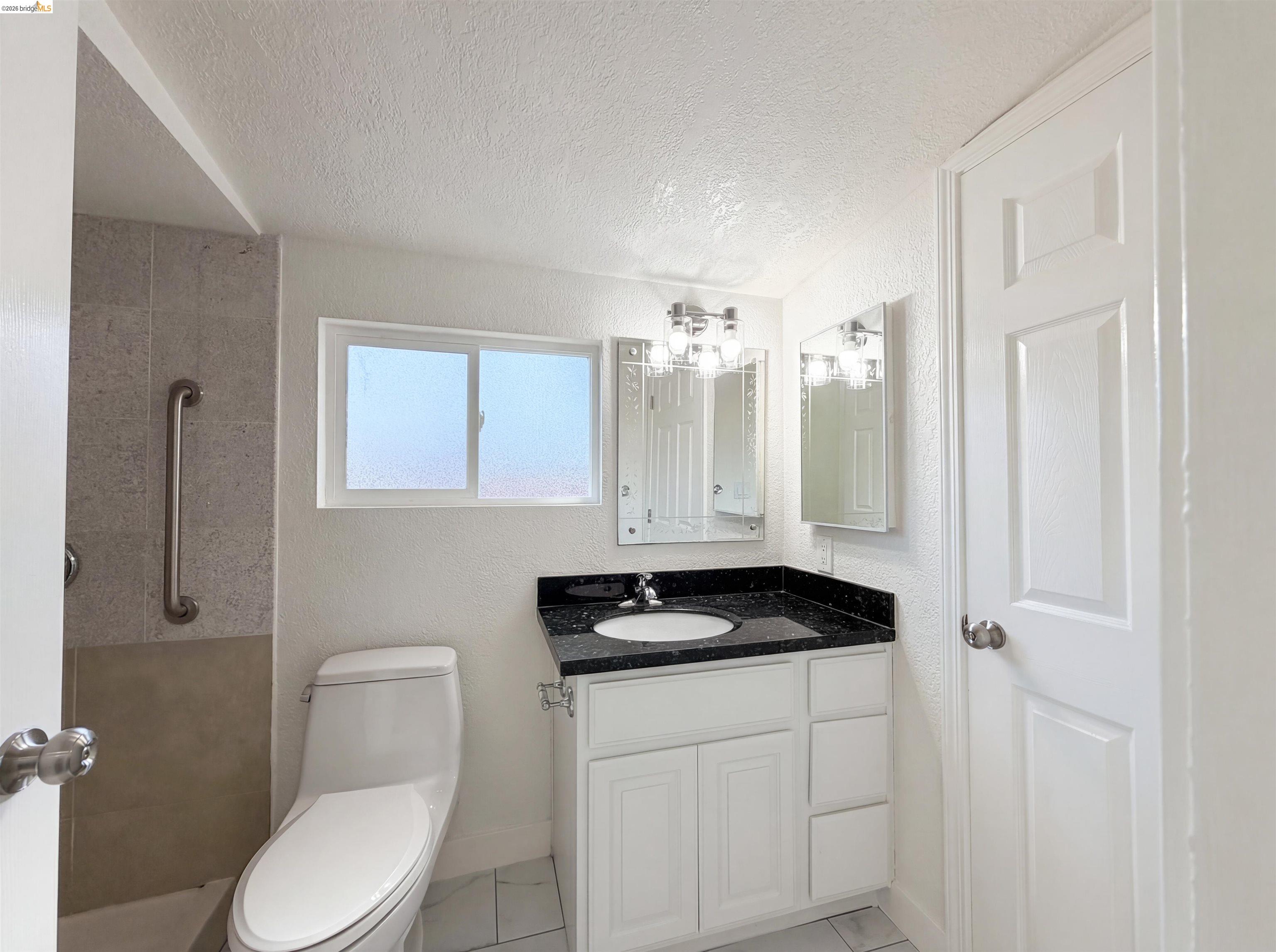 1564 South Wolfe Road Sunnyvale, CA 94087 - Photo 23 of 27 Full bathroom featuring vanity, a textured ceiling, a textured wall, a tile shower, and a chandelier