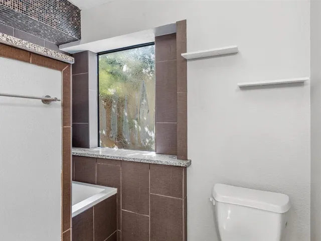 a bathroom with a granite countertop sink mirror vanity and toilet