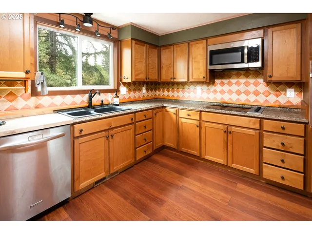 a kitchen with granite countertop wooden cabinets a stove a sink and a large window