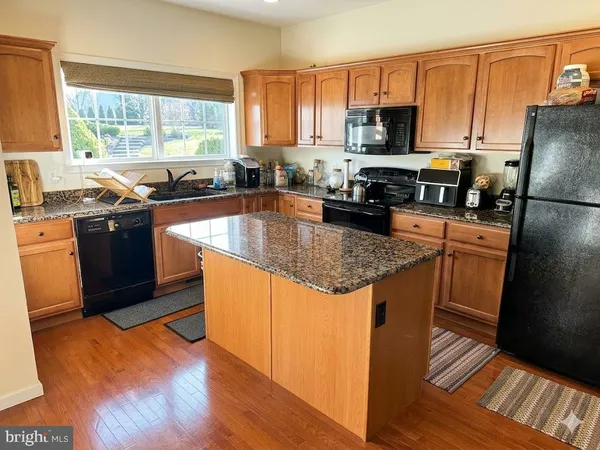 a kitchen with kitchen island granite countertop a sink cabinets and stainless steel appliances