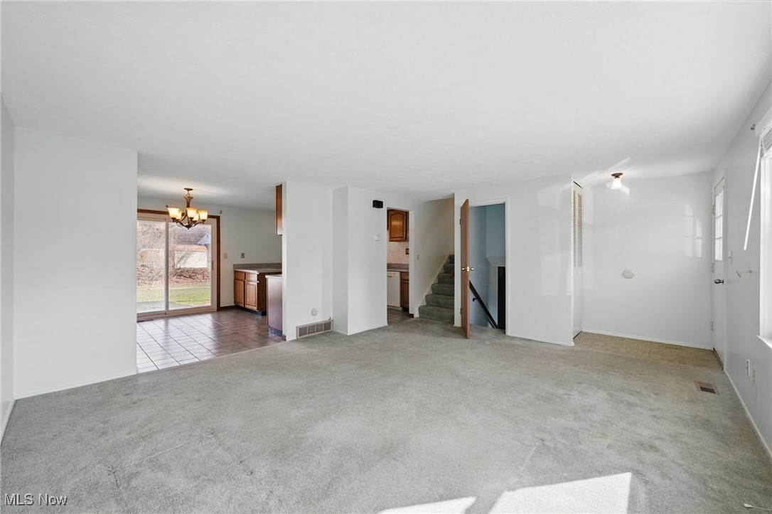 803 Renninger Road Akron, OH 44319 - Photo 5 of 44 Unfurnished living room with stairway, a notable chandelier, carpet, and visible vents