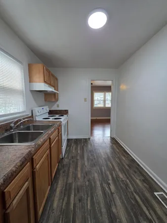 a kitchen that has a sink wooden floor stainless steel appliances and cabinets