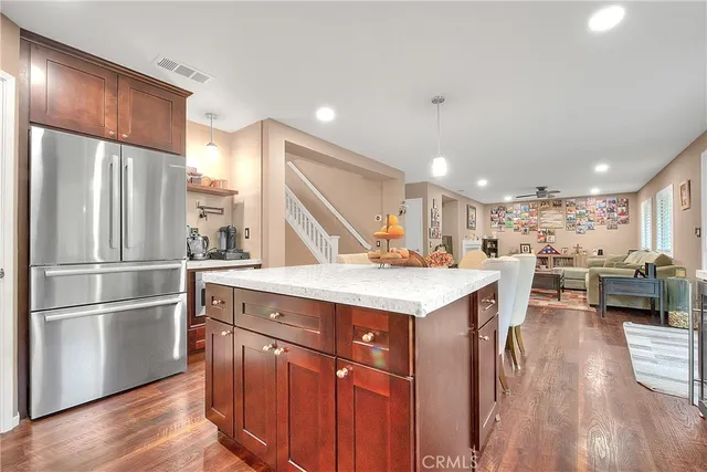 a kitchen with kitchen island a large counter top space stainless steel appliances and wooden floor