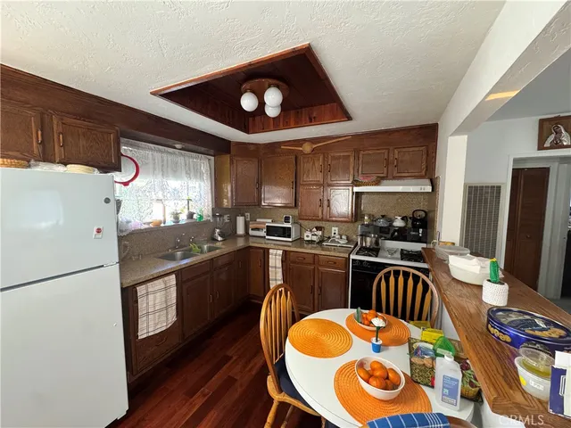 a kitchen with stainless steel appliances granite countertop a stove a refrigerator a sink a dining table and chairs with wooden floor