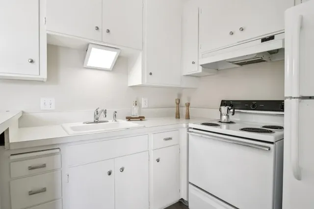 a kitchen with white cabinets sink and stove