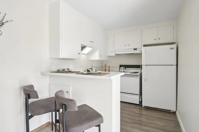 a kitchen with a refrigerator a stove a dining table and chairs