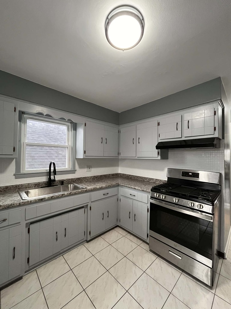 6138 South Kilpatrick Avenue, Unit 2 Chicago, IL 60629 - Photo 18 of 19 a kitchen with granite countertop a stove a sink and a microwave