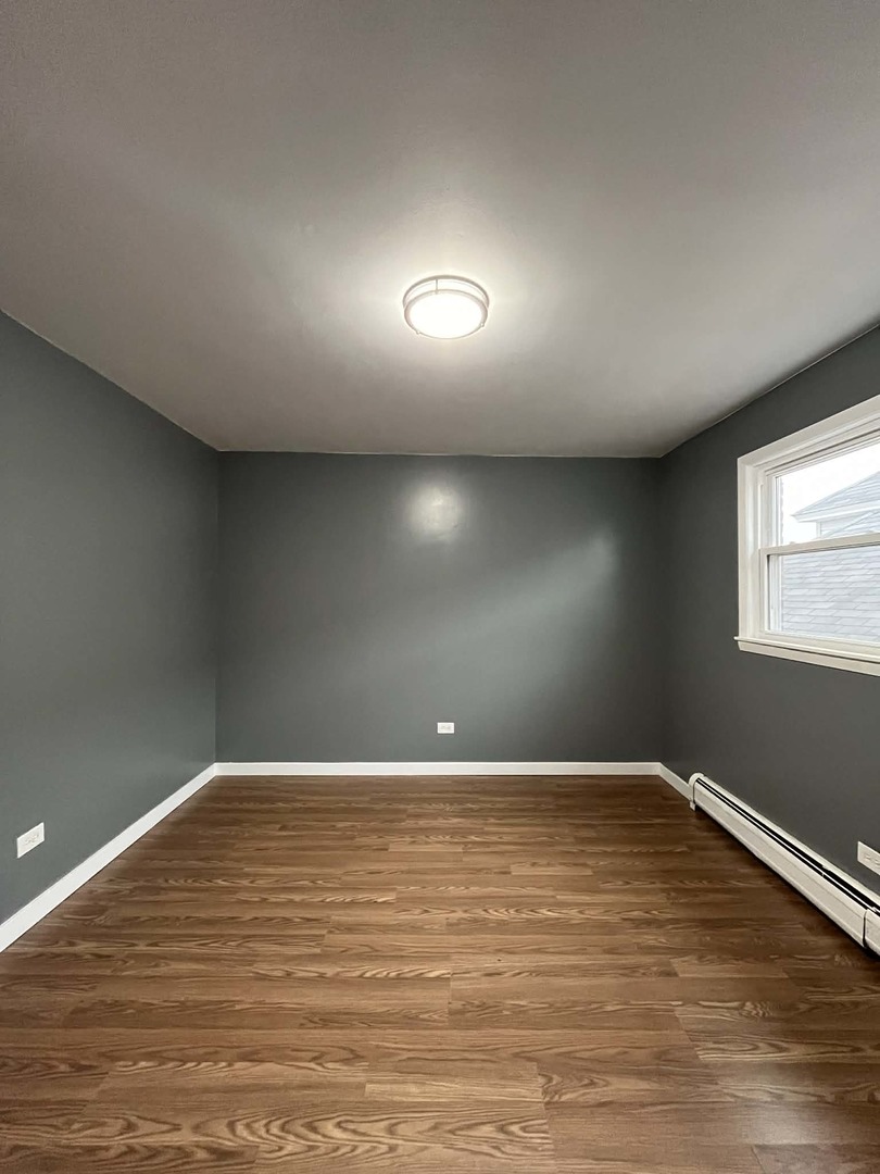 6138 South Kilpatrick Avenue, Unit 2 Chicago, IL 60629 - Photo 7 of 19 a view of an empty room with wooden floor and a window