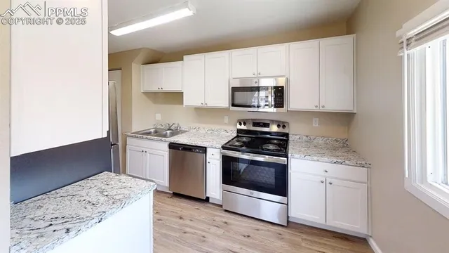 a kitchen with stainless steel appliances granite countertop a stove a sink and a microwave