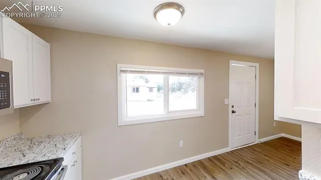 an empty room with wooden floor and windows