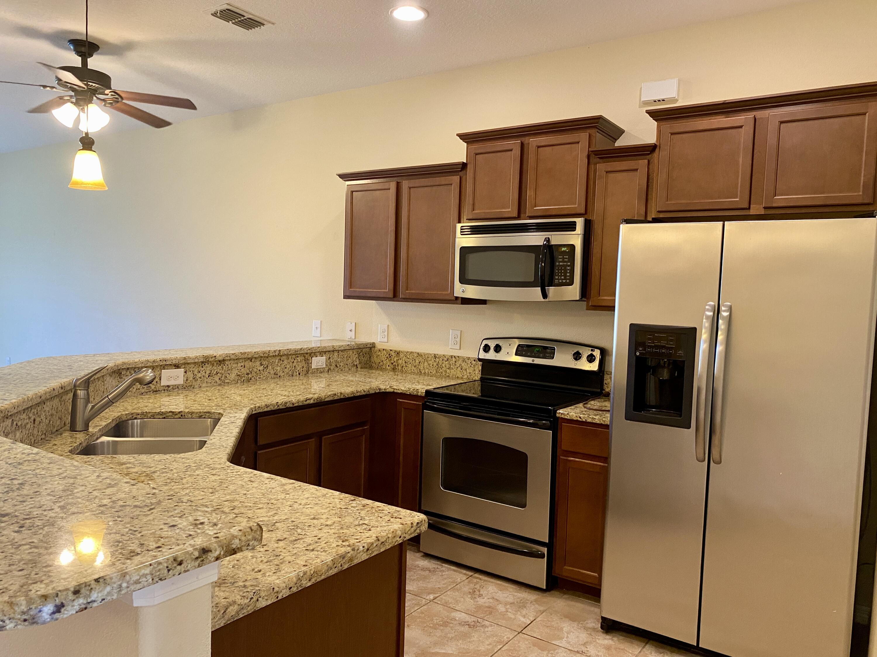 3490 Funston Circle Melbourne, FL 32940 - Photo 2 of 25 a kitchen with kitchen island granite countertop a sink a stove and refrigerator