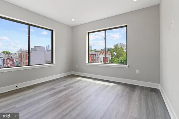 an empty room with wooden floor and windows