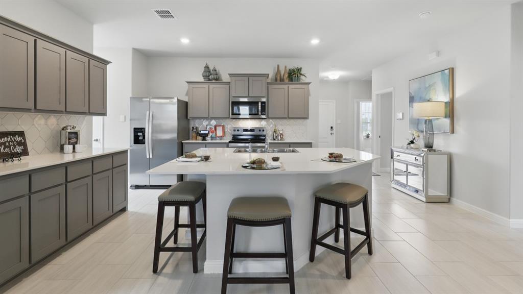 a kitchen with stainless steel appliances kitchen island a table chairs sink and cabinets
