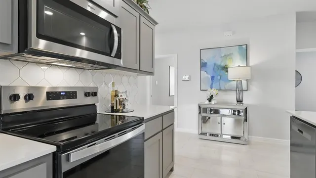 a kitchen with stainless steel appliances kitchen island a table chairs sink and cabinets