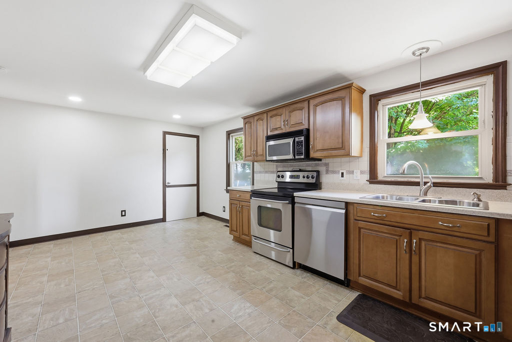 630 South Elm Street Wallingford, CT 06492 - Photo 8 of 30 a kitchen with stainless steel appliances granite countertop a stove top oven a sink dishwasher a refrigerator and a microwave oven with wooden floor
