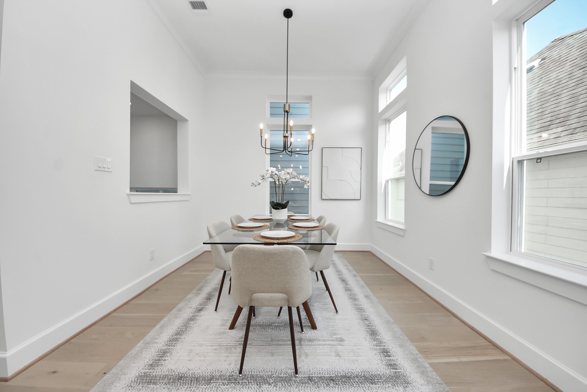 925 Fisher Street, Unit C Houston, TX 77018 - Photo 15 of 47 Welcome to this bright, modern dining room, featuring a sleek glass table with seating for six under a contemporary chandelier. Large windows fill the space with natural light, while the neutral color palette and minimalist decor create an inviting atmosphere perfect for meals and gatherings.
