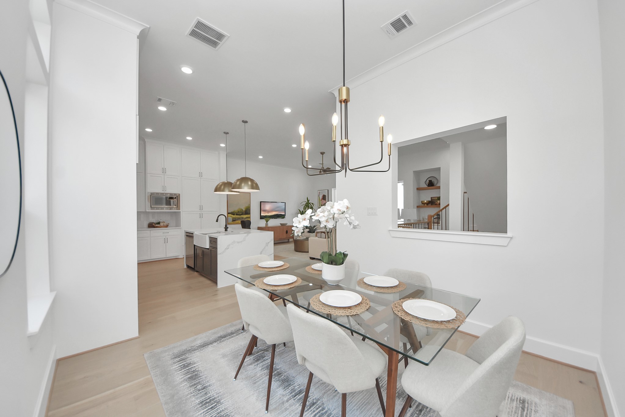 925 Fisher Street, Unit C Houston, TX 77018 - Photo 16 of 47 Step into this modern, open-concept dining and kitchen area, where a glass dining table with elegant seating sits beneath a contemporary chandelier. The bright kitchen features white cabinetry, stainless steel appliances, and a farmhouse sink, while light wood flooring and stylish decor create an airy, welcoming atmosphere perfect for entertaining or daily living.