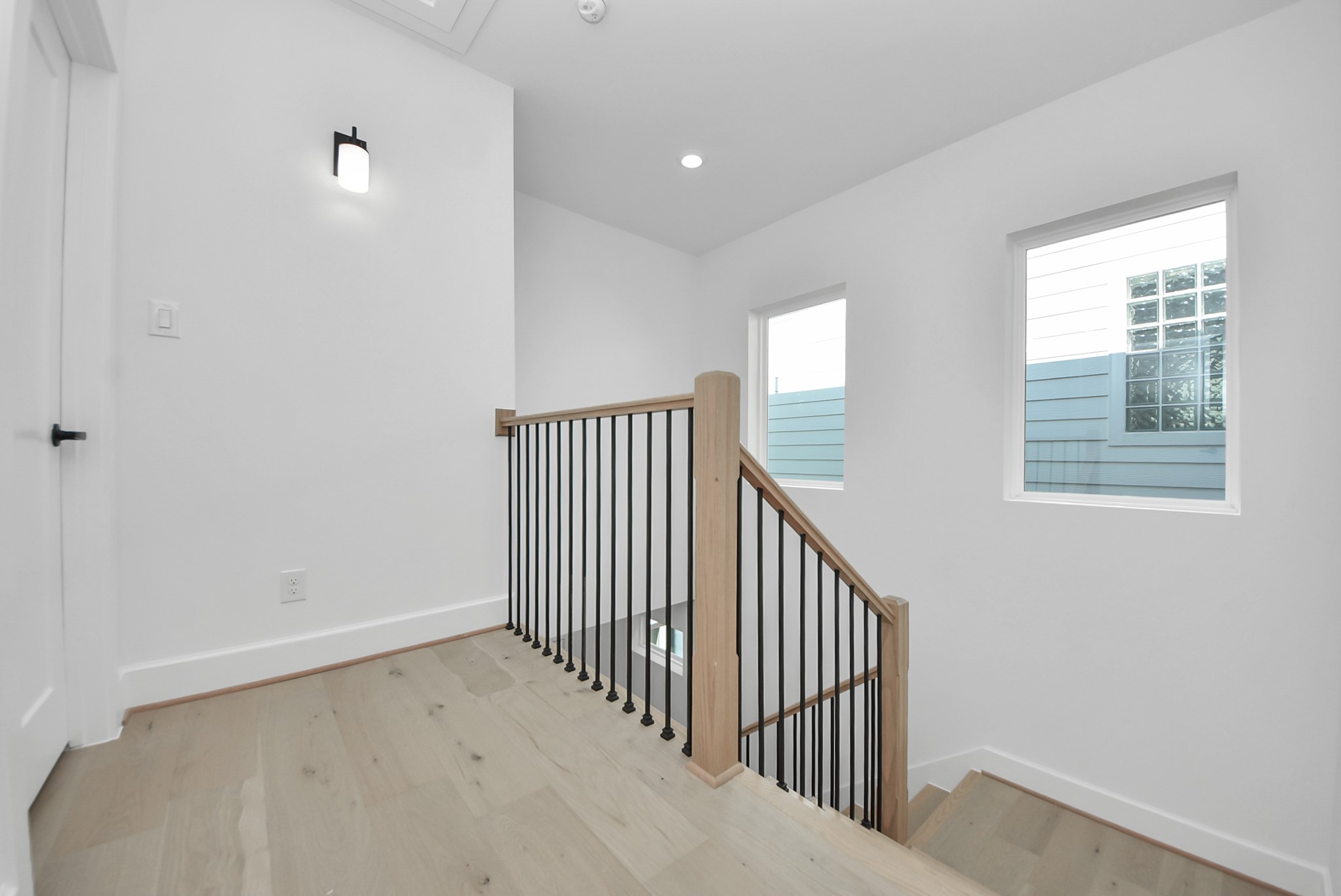 925 Fisher Street, Unit C Houston, TX 77018 - Photo 29 of 47 This bright, modern stairway landing features light wood flooring and a sleek black metal railing. Two large windows flood the space with natural light, creating an open and inviting atmosphere.