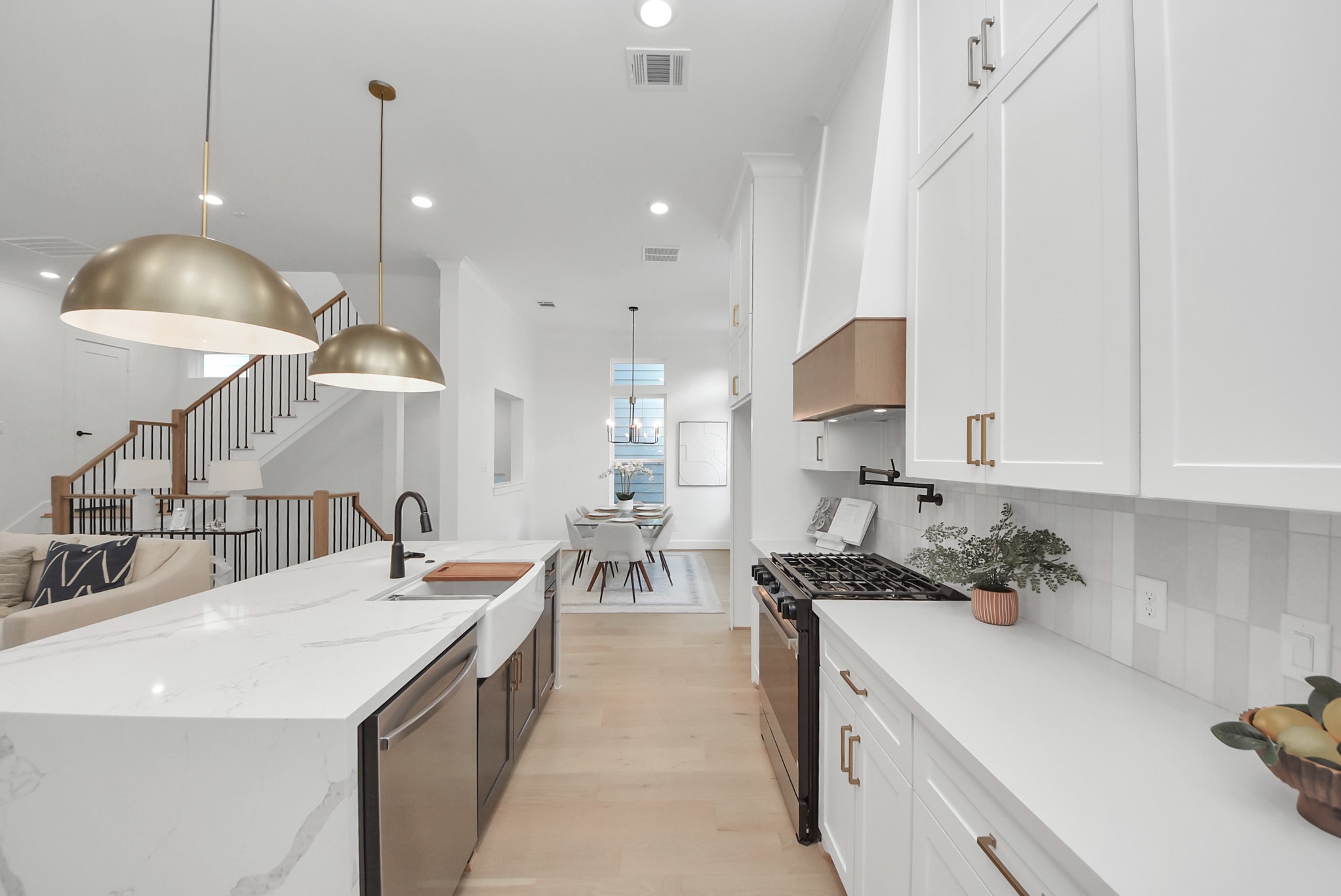 925 Fisher Street, Unit C Houston, TX 77018 - Photo 35 of 47 Experience this modern, open-concept kitchen with sleek white cabinetry, a large marble island, and elegant pendant lighting. The kitchen flows seamlessly into the dining area, with a view of the staircase leading to the upper floor, enhancing the spacious feel.