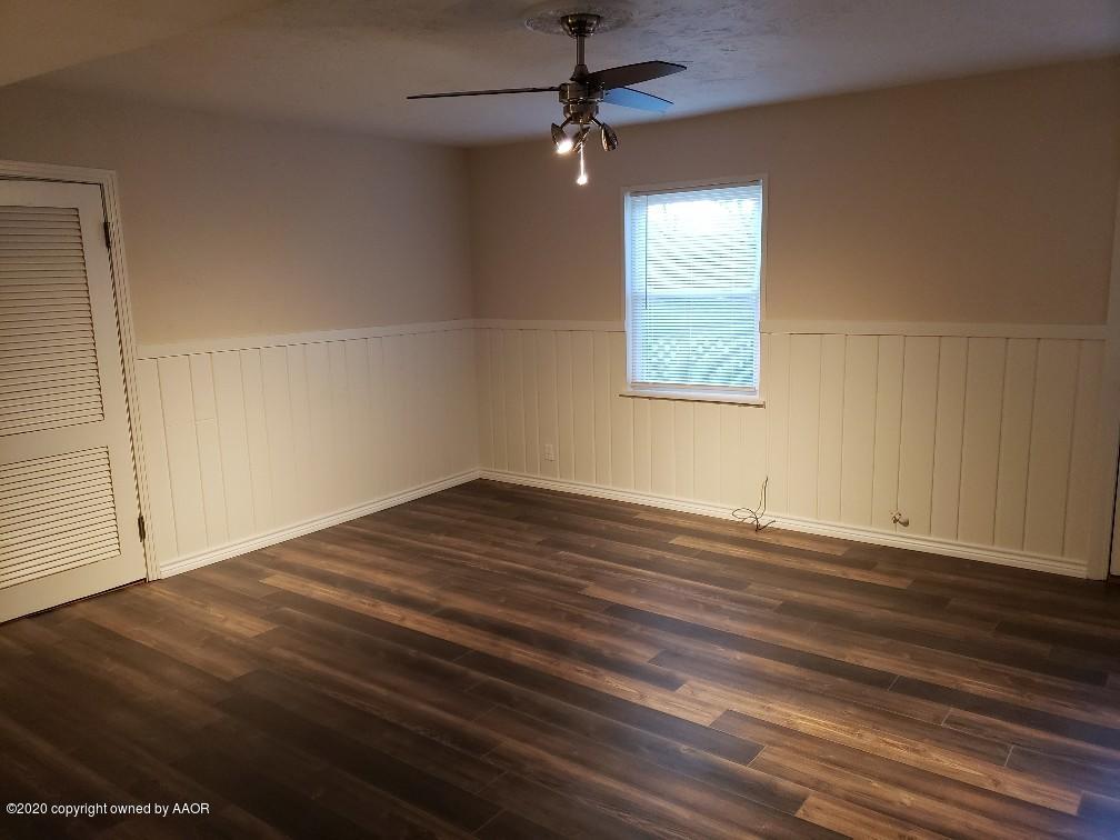 4408 South Ong Street Amarillo, TX 79110 - Photo 6 of 23 an empty room with wooden floor chandelier fan and windows