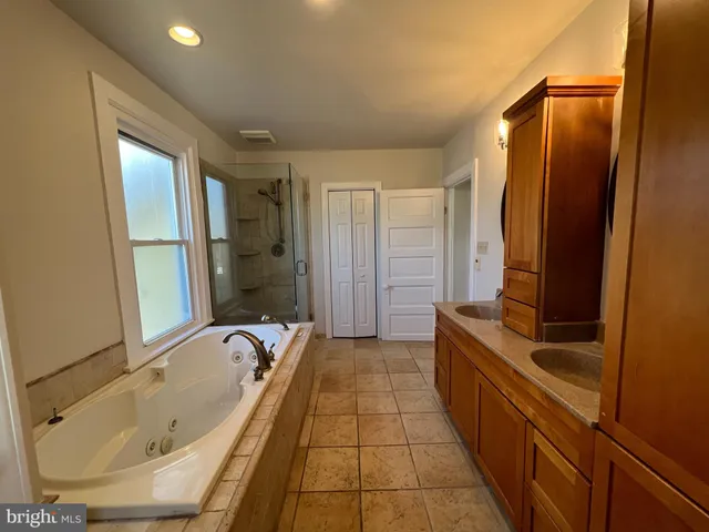 a bathroom with a tub a sink and a large mirror