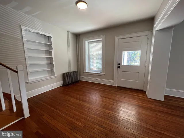 an empty room with wooden floor closet and windows