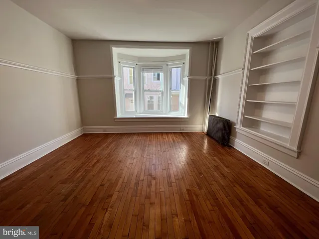 a view of wooden floor in an empty room with a window