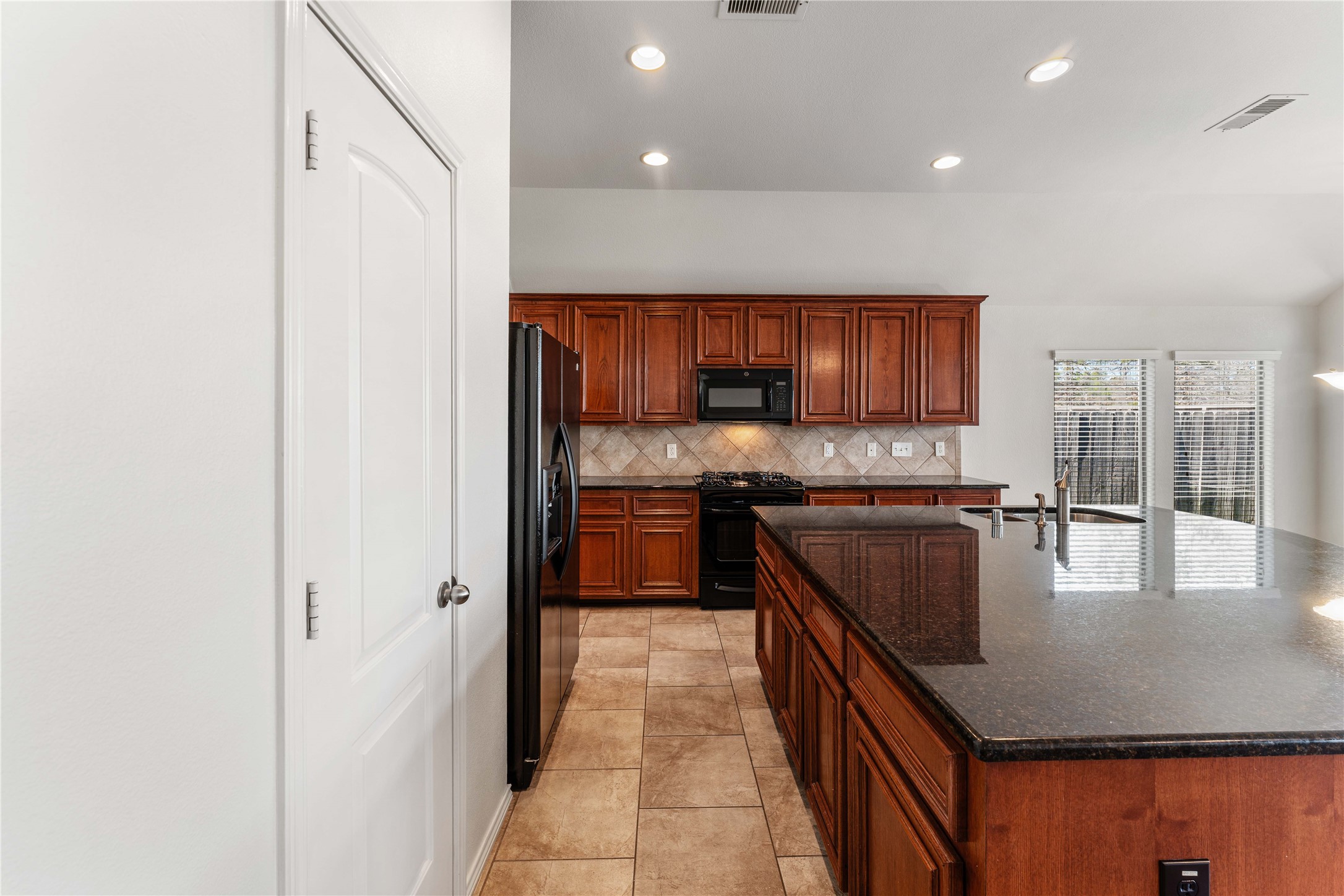 1602 Eden Meadows Drive Spring, TX 77386 - Photo 15 of 42 a kitchen with kitchen island granite countertop wooden cabinets a stove a sink and a refrigerator with wooden floor
