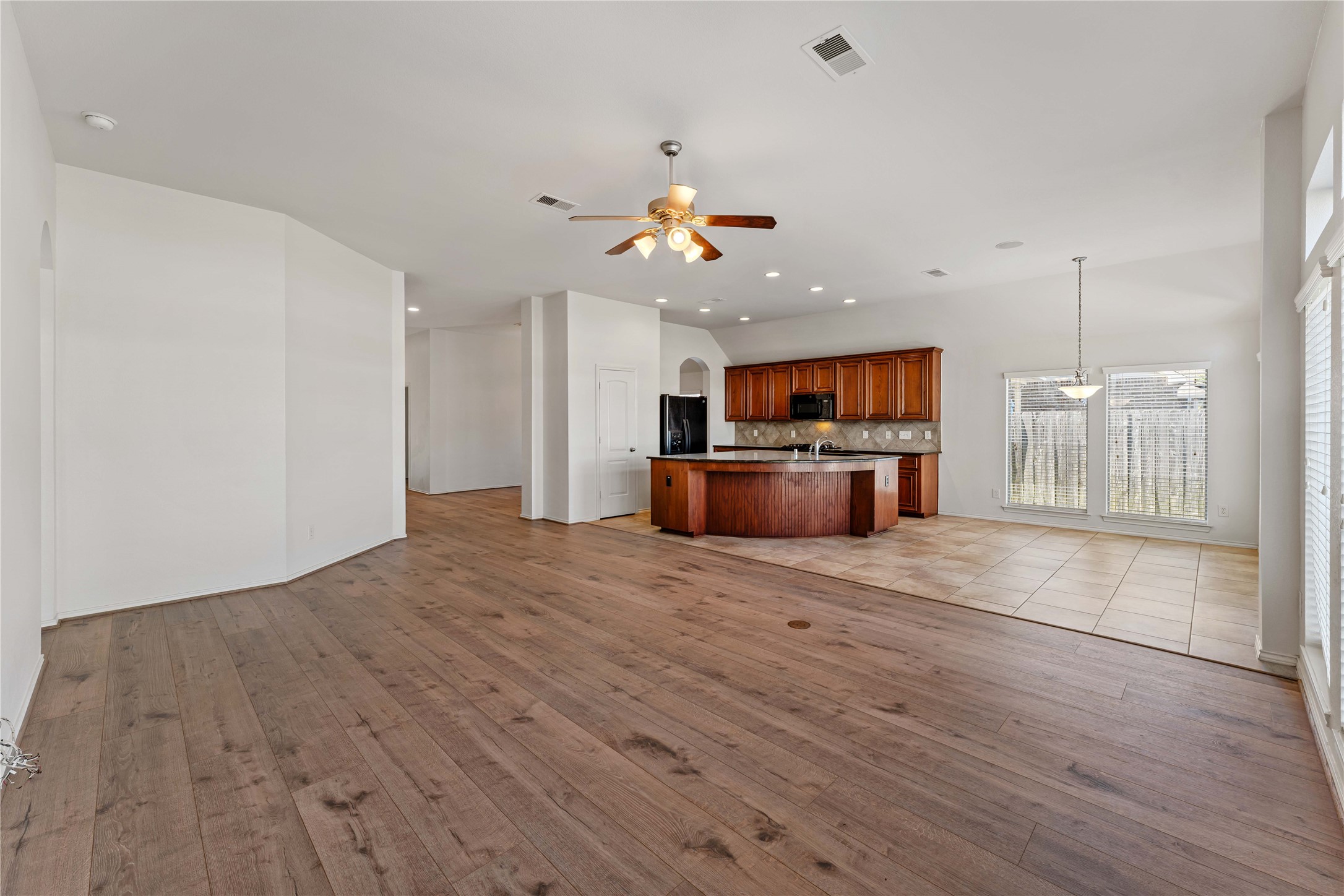 1602 Eden Meadows Drive Spring, TX 77386 - Photo 10 of 42 an empty room with wooden floor a ceiling fan window and a kitchen view