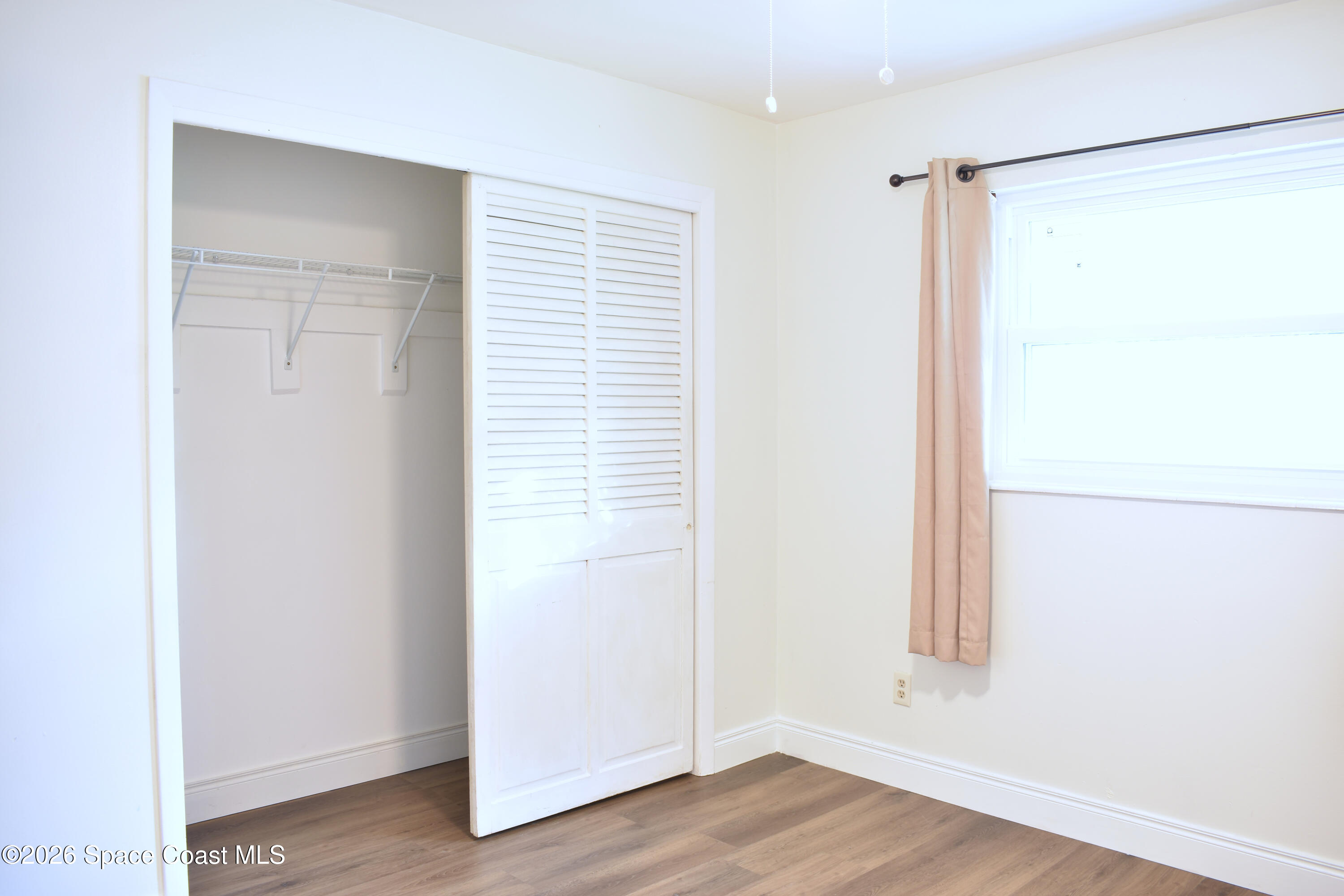 1413 Floyd Drive Rockledge, FL 32955 - Photo 13 of 17 a view of an empty room with wooden floor and a window