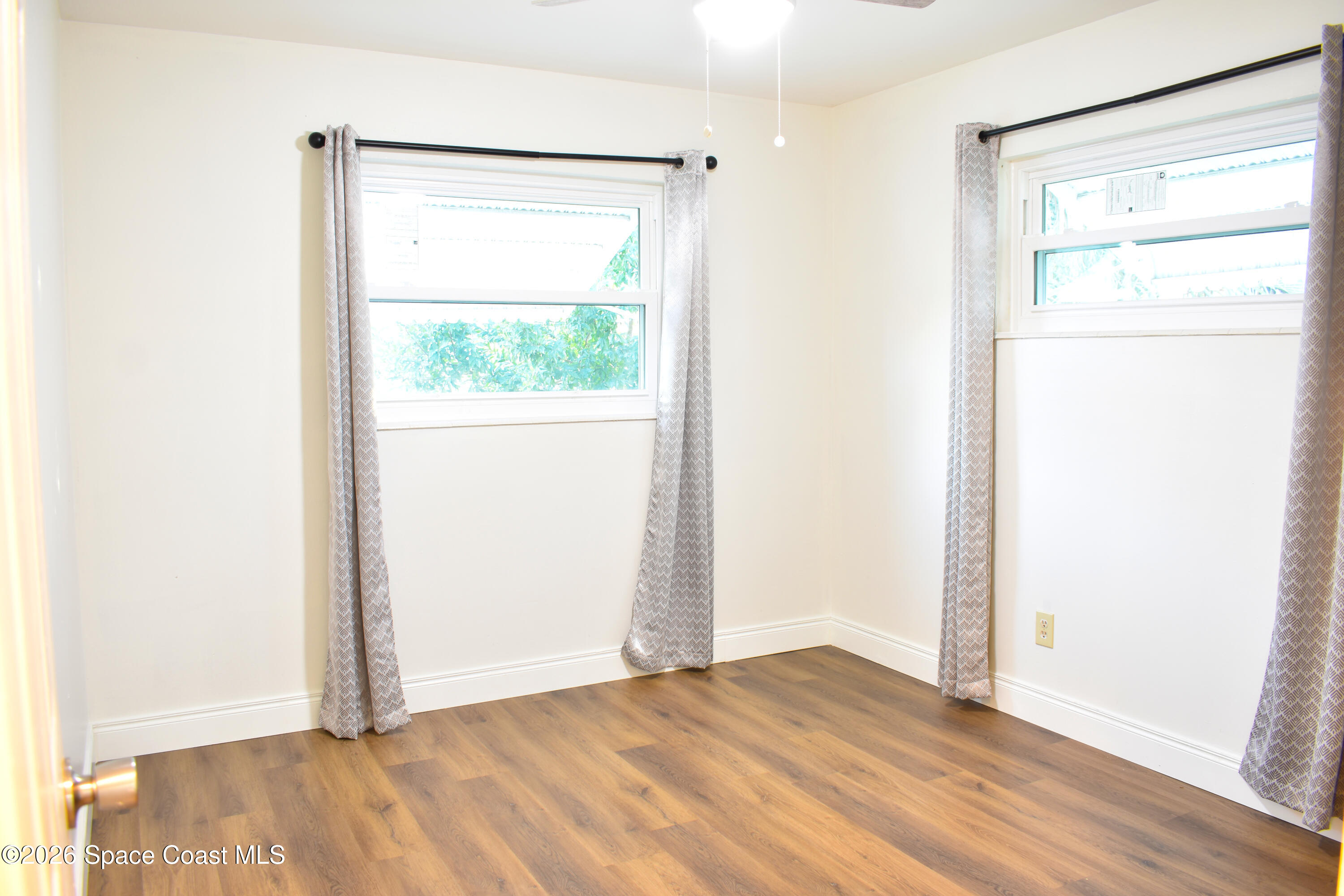 1413 Floyd Drive Rockledge, FL 32955 - Photo 14 of 17 a view of an empty room with wooden floor and a window