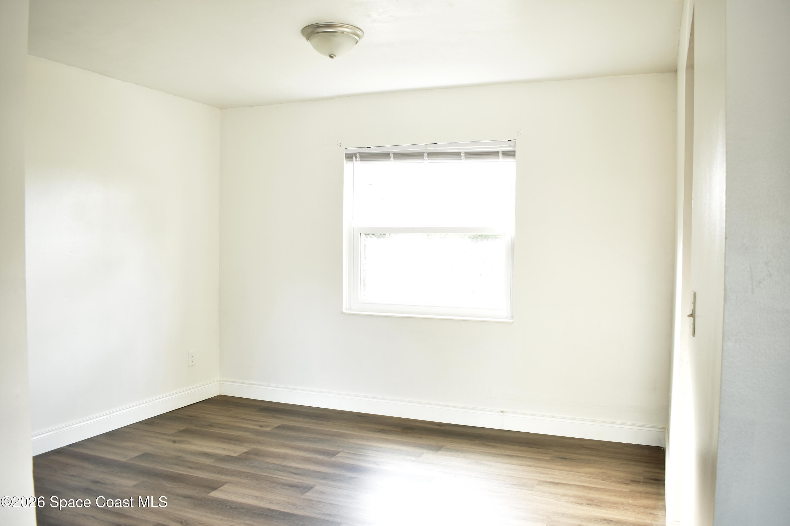 1413 Floyd Drive Rockledge, FL 32955 - Photo 10 of 17 a view of an empty room with wooden floor and a window