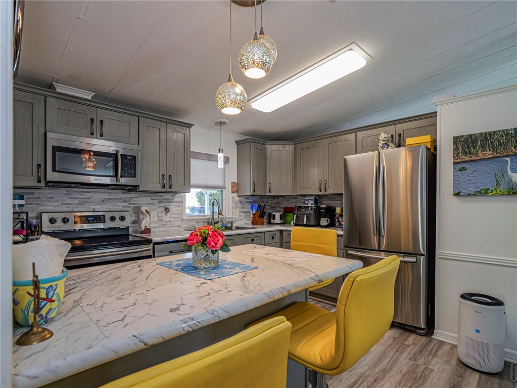 409 Avocado Drive Sebastian, FL 32976 - Photo 16 of 35 a kitchen with stainless steel appliances granite countertop a refrigerator a stove top oven a sink dishwasher and white cabinets with wooden floor