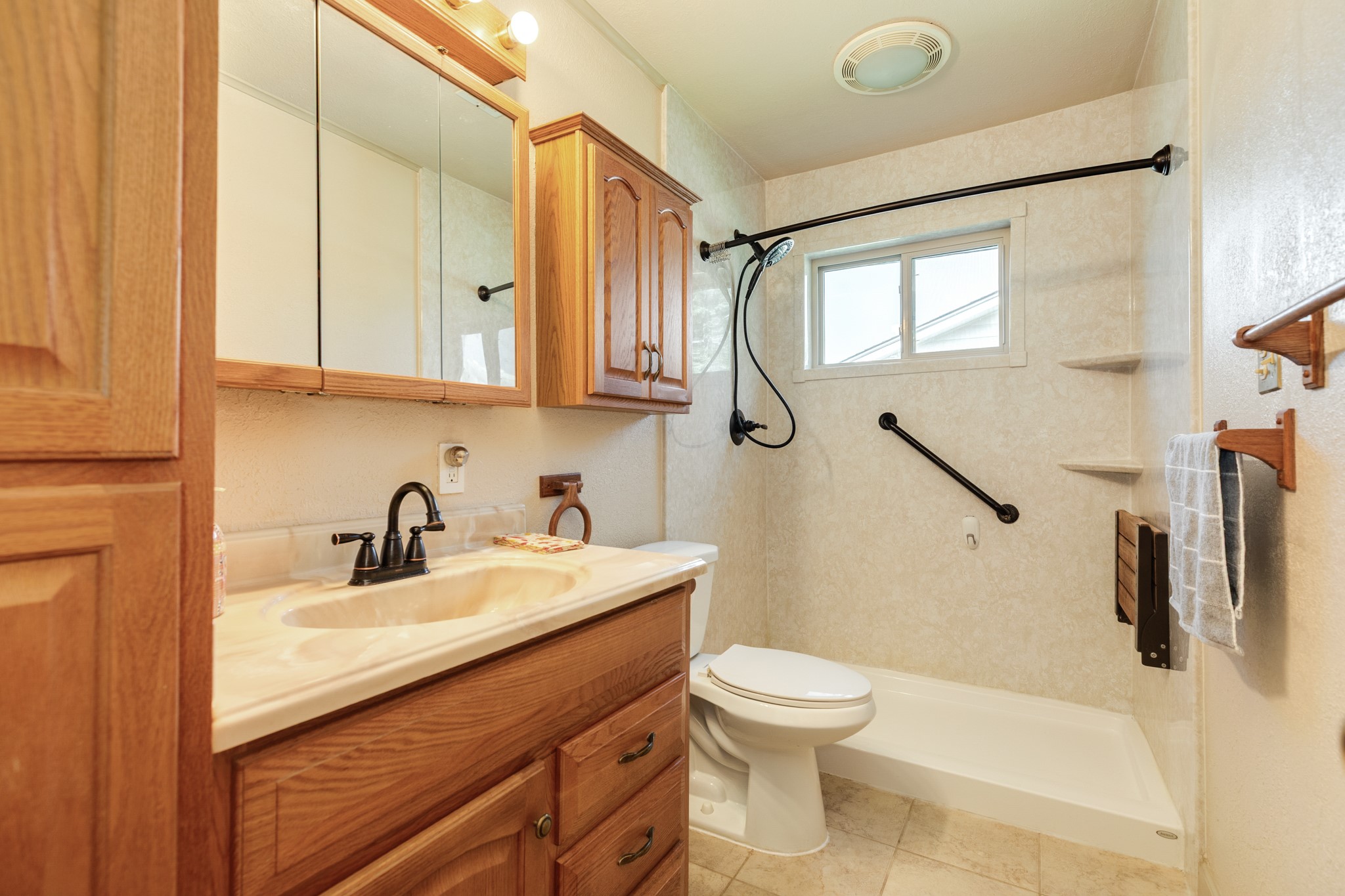 616 Bel Road Kemah, TX 77565 - Photo 16 of 23 Full bath with wood cabinetry and additional storage, combination tub/shower combination with surround, built-in corner shelving, window, and grab bar.