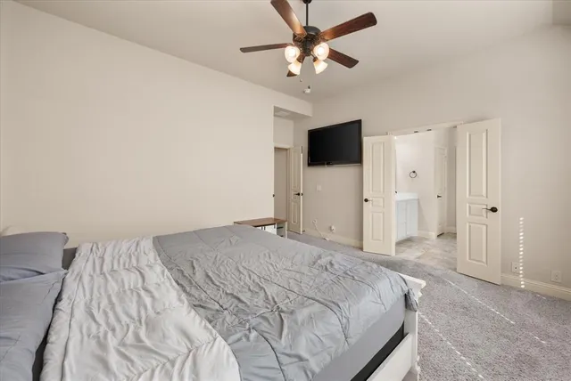 a spacious bedroom with a bed and a flat screen tv