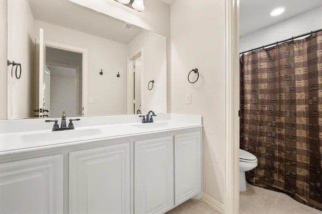 a bathroom with a double vanity sink toilet and a mirror