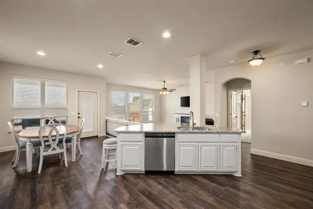 a room with stainless steel appliances kitchen island granite countertop a sink and cabinets