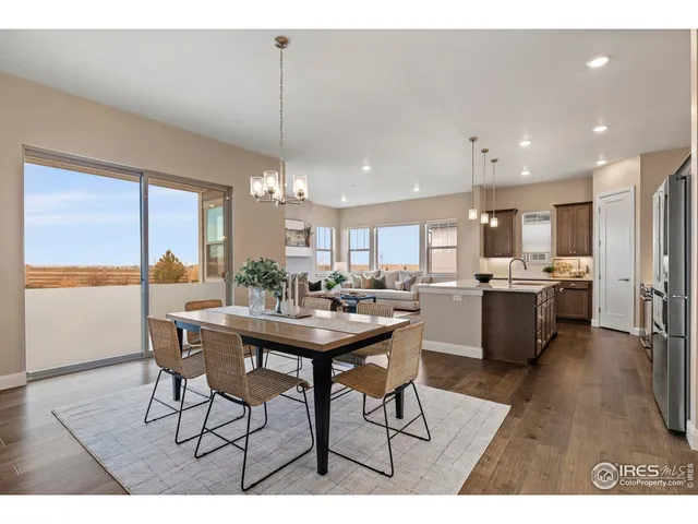 a open kitchen with stainless steel appliances kitchen island granite countertop a dining table chairs and a refrigerator