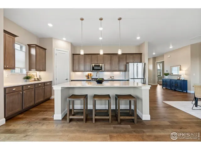 a kitchen with a dining table chairs wooden floor appliances and cabinets