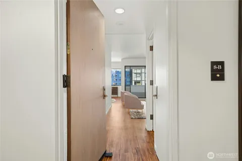 a view of a hallway with wooden floor and a living room